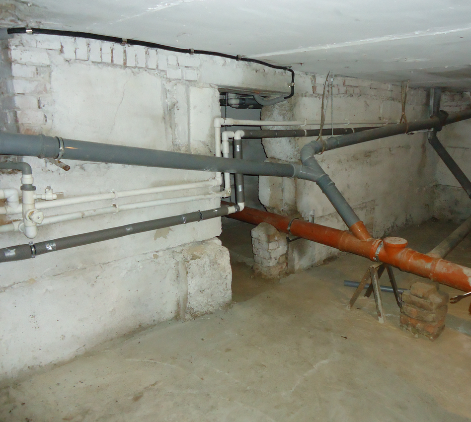 Канализация в подвале многоквартирного дома: видна лежневка и подключенные к ней стояки